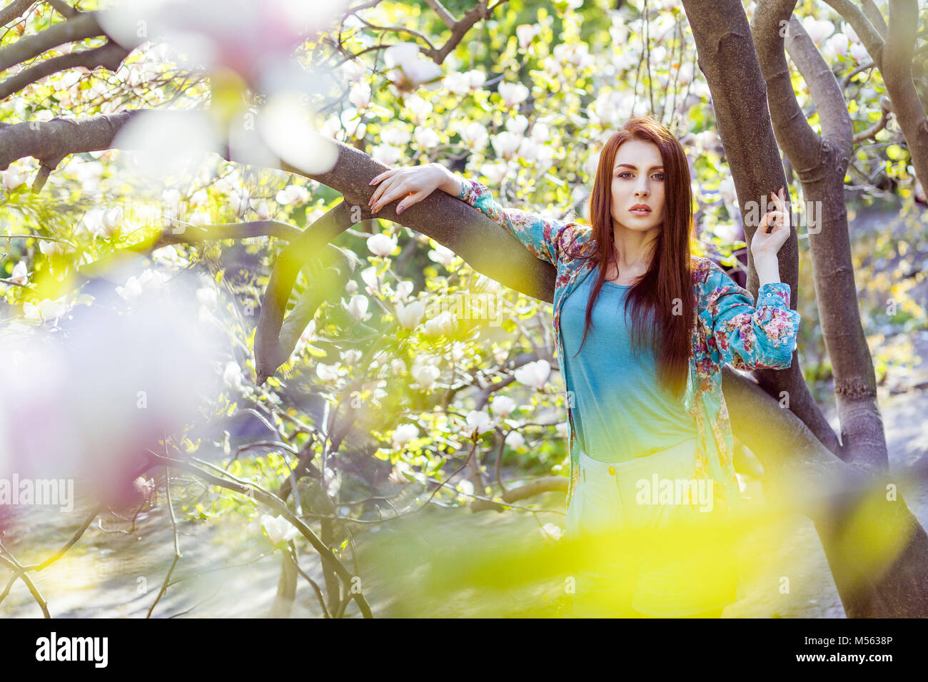 Portrait of young beautiful fashion model near magnolia flower posing