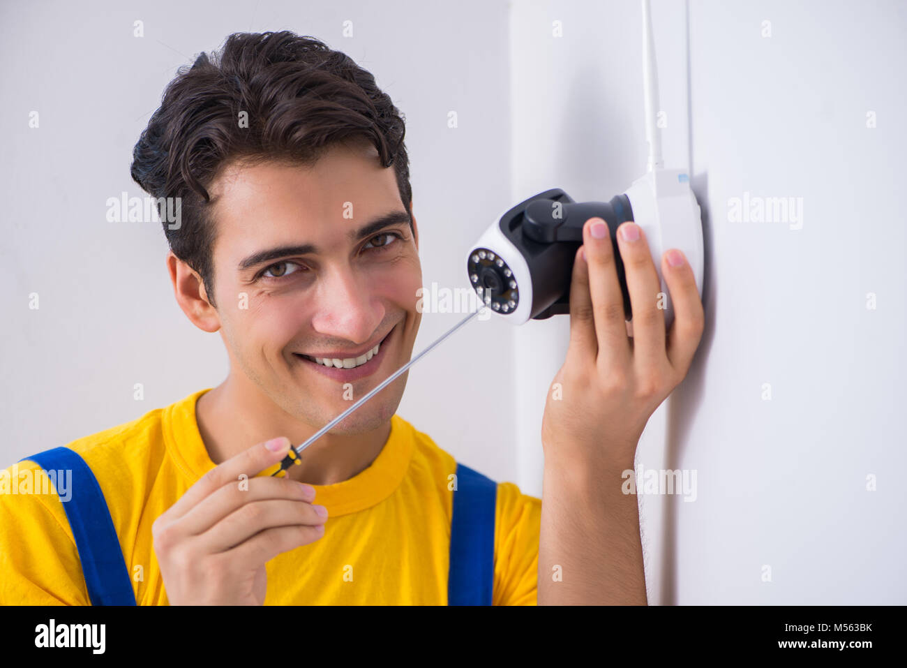 Contractor installing surveillance CCTV cameras in office Stock Photo