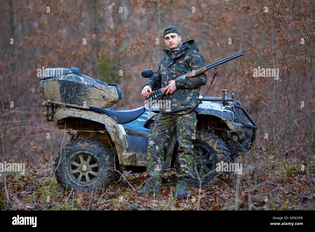 Young hunter on a quad bike searching for game in the forest Stock