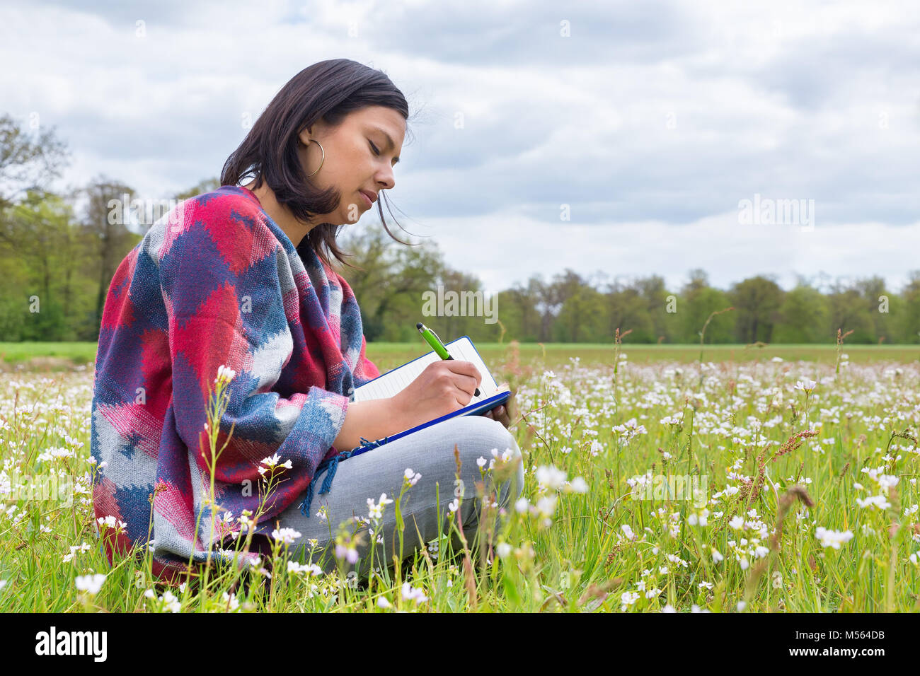 Woman writes in meadow with spring flowers Stock Photo