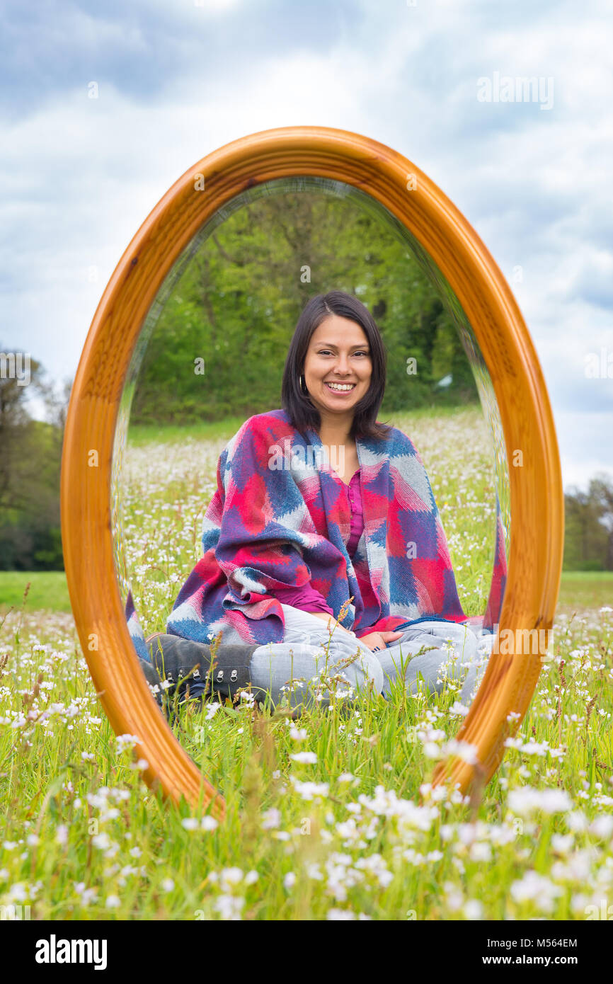 Mirror in spring meadow with sitting pretty woman Stock Photo