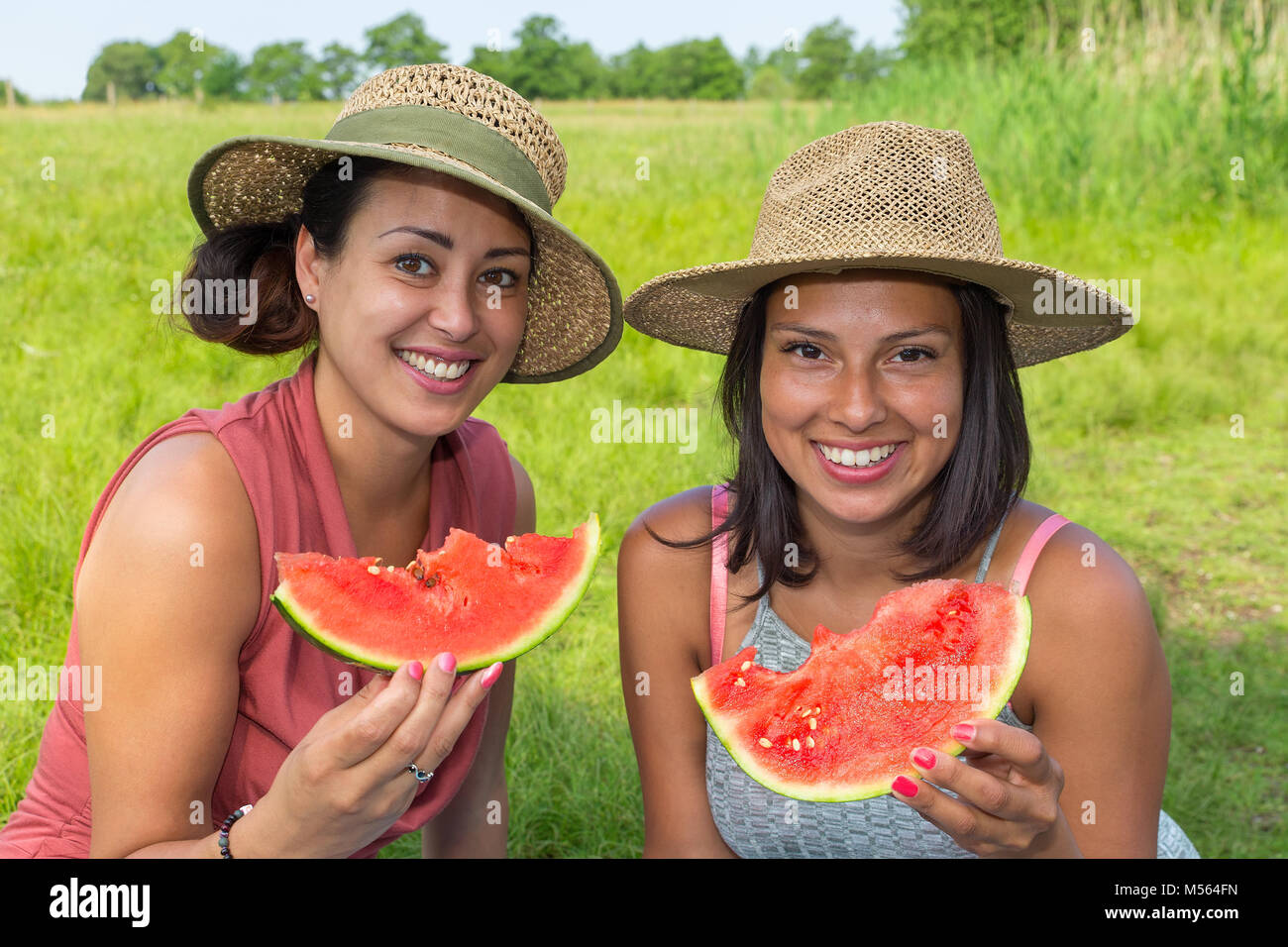 Two women eating fresh melon in nature Stock Photo