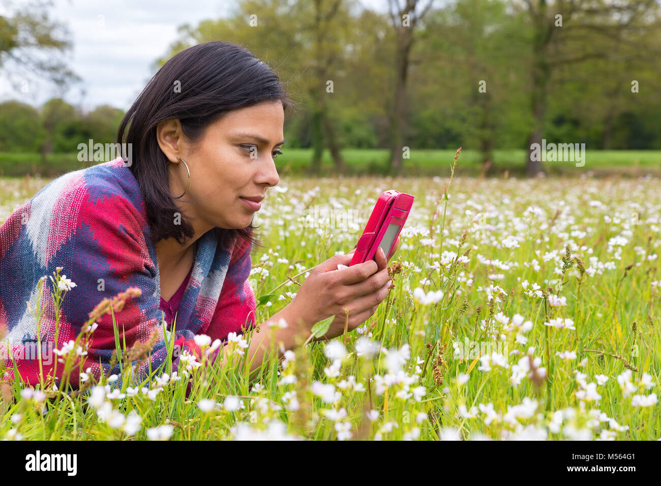 Woman lying in  meadow phoning mobile Stock Photo