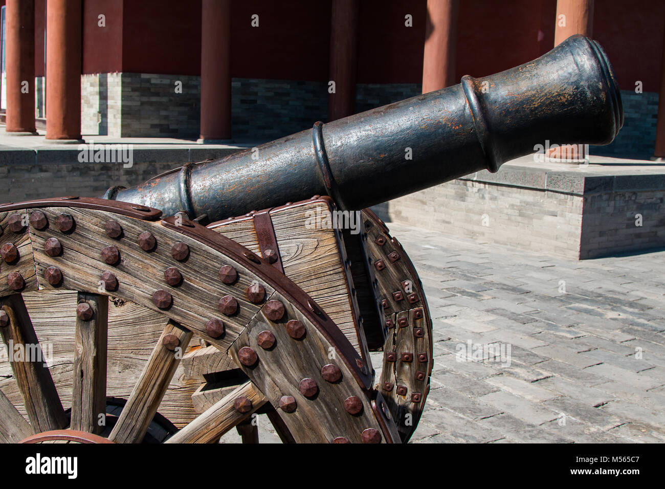 Rusty cannon on wooden wheeled cart. Stock Photo