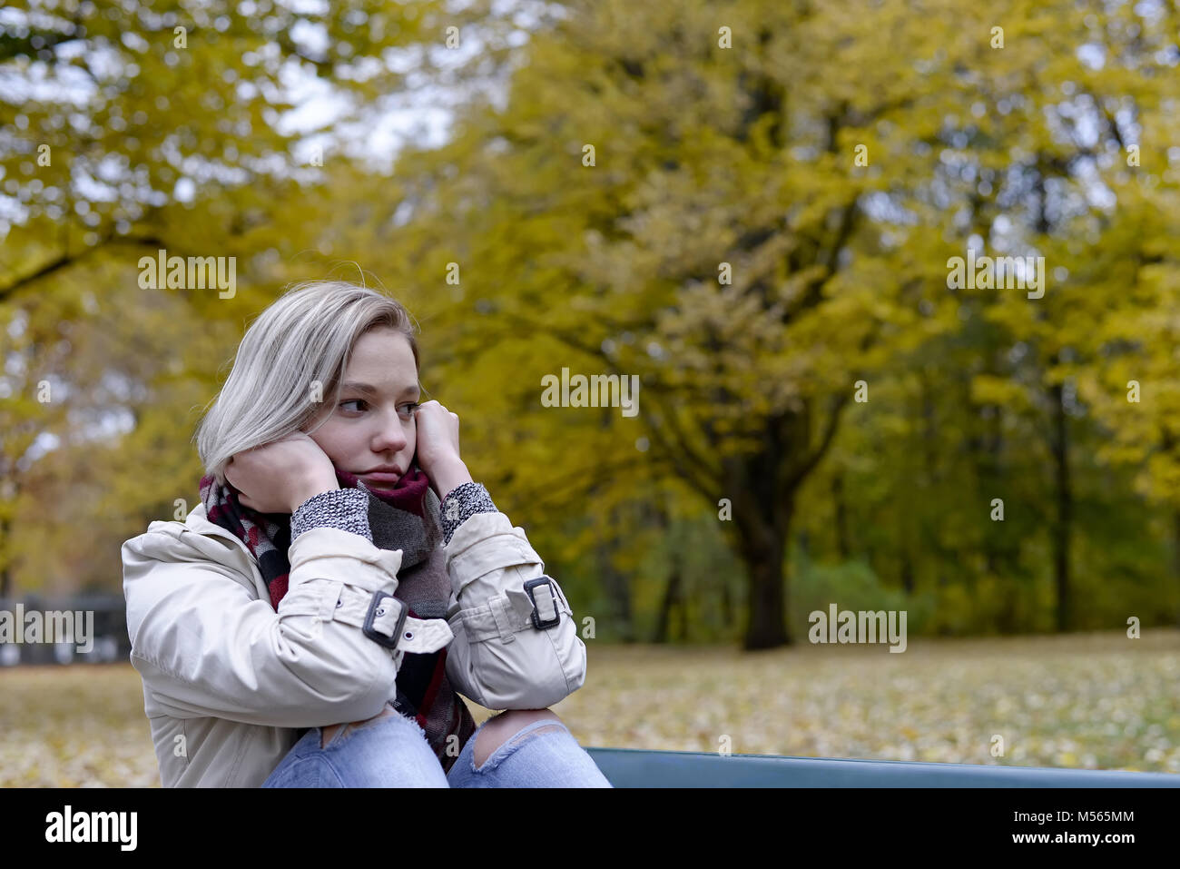 lonely young woman sitting on bench Stock Photo - Alamy