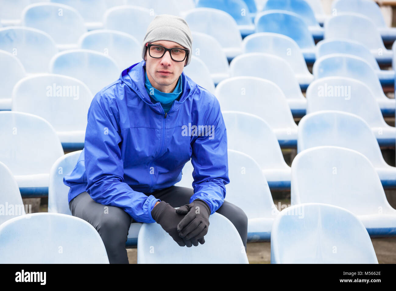 Portrait of professional athlete looking at camera sitting on stadium seat. Stock Photo
