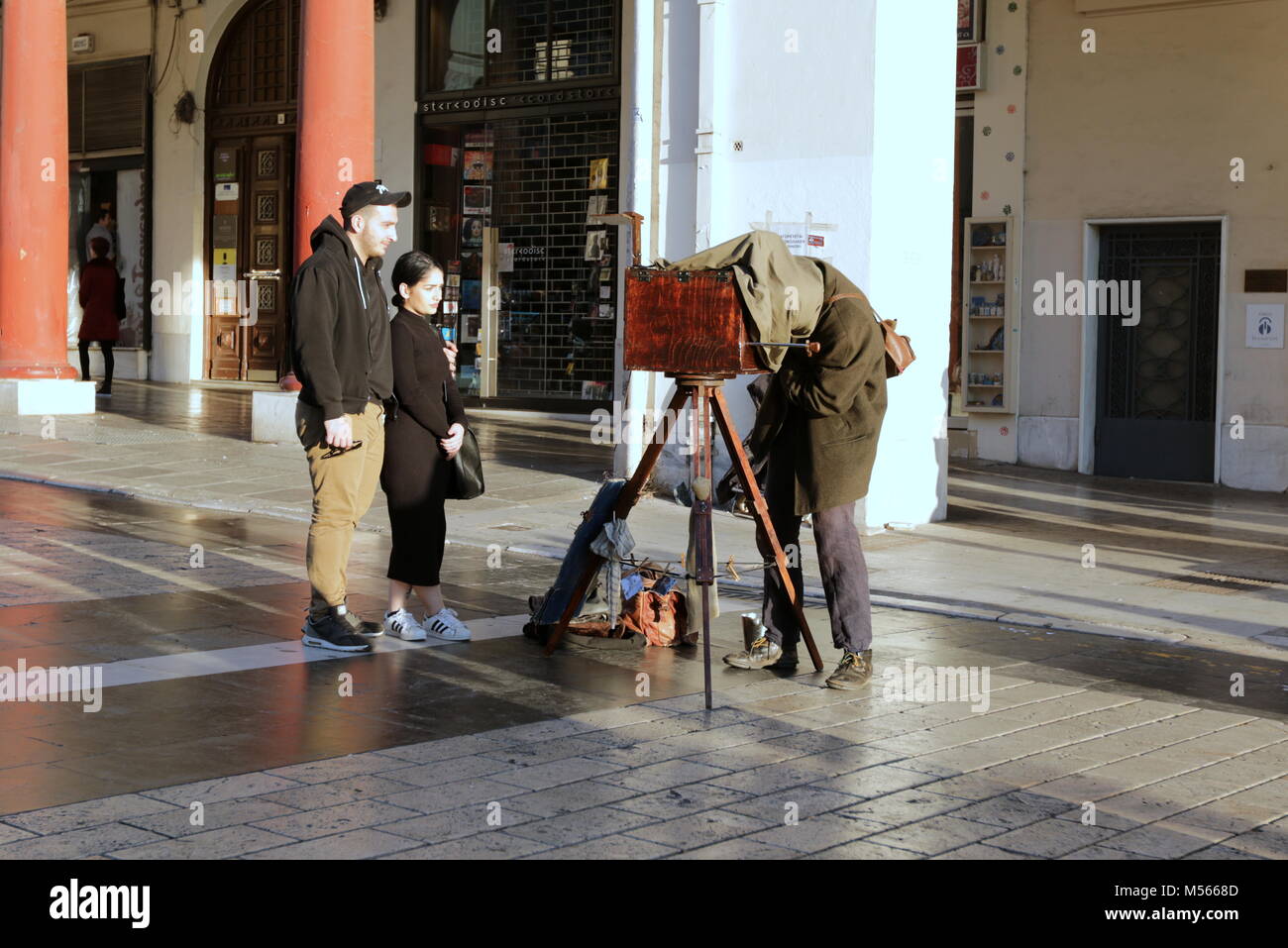 Photographer with a vintage glass plate wooden camera under dark cloth