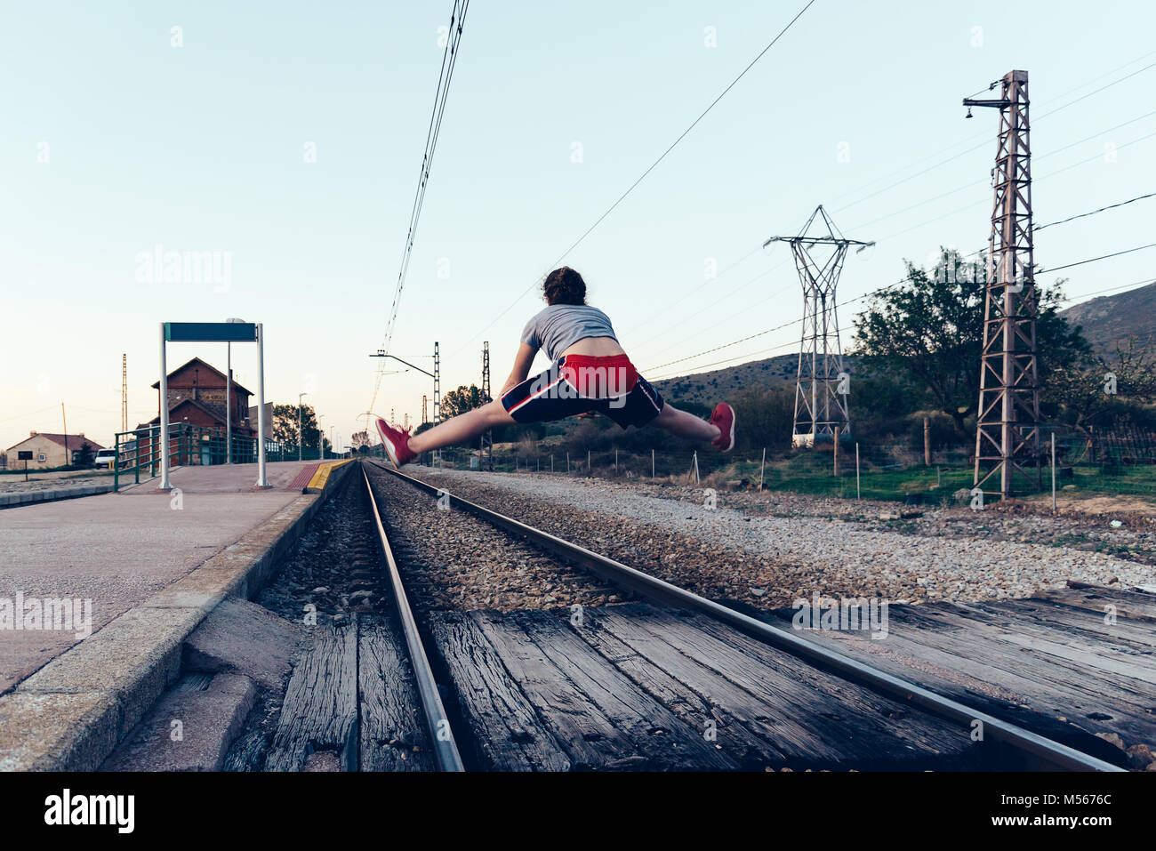 Young woman is jumping on the railroad tracks at old railroad station