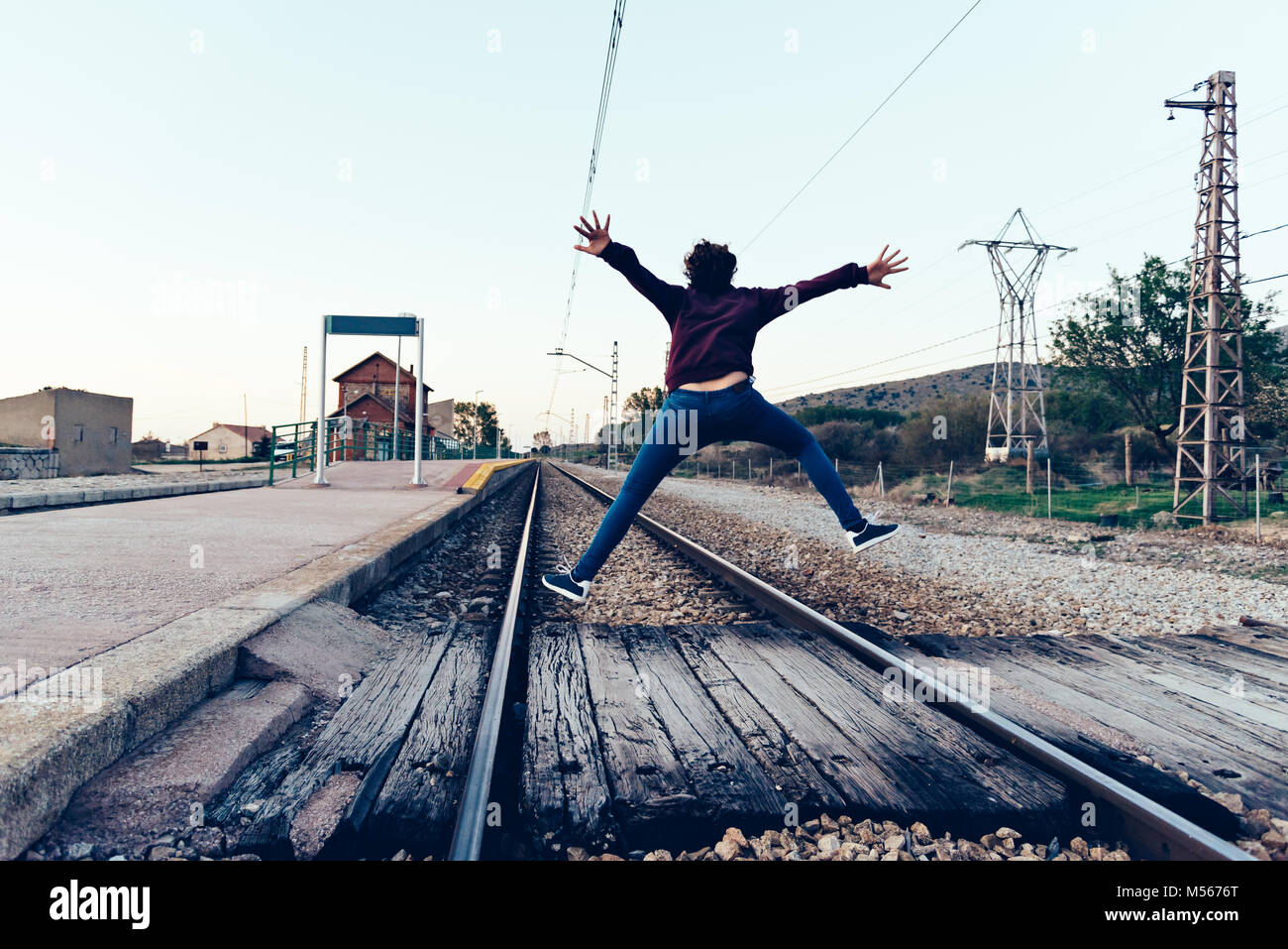 Young woman is jumping on the railroad tracks at old railroad station