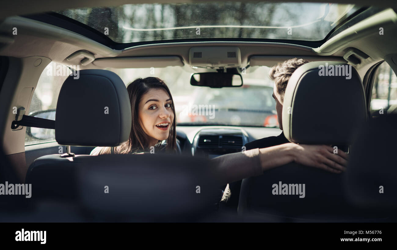 Young woman in a car,female driver looking at the passenger and smiling.Enjoying the ride,traveling,road trip concept.Driver feeling happy and safe.Le Stock Photo
