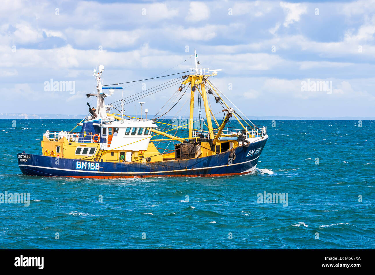 A fishing vessel leaves harbour and sets sail to the fishing grounds. Stock Photo