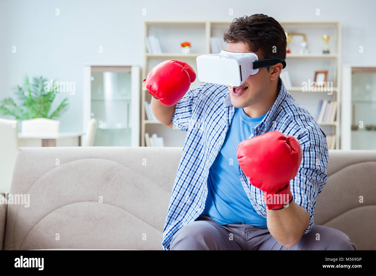 Man wearing virtual reality VR glasses playing boxing game Stock Photo