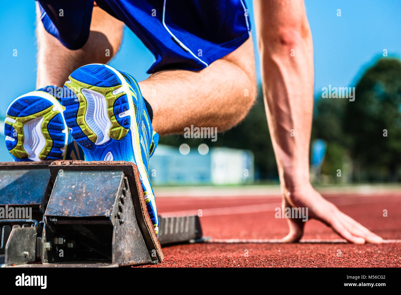 Runner before start signal on starting block of sprint track in sport stadium Stock Photo
