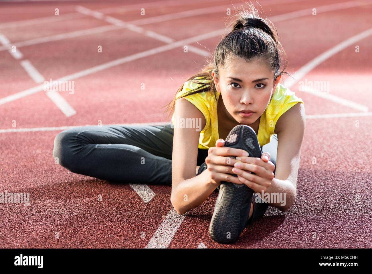 woman athlete stretching on racing track before sprint Stock Photo