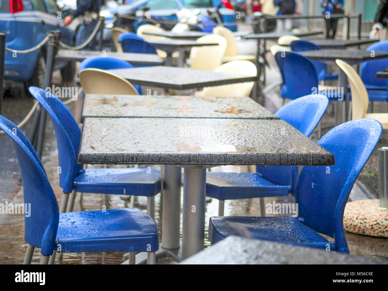 Bar tables and chairs under the rain blue plastic chairs and grey