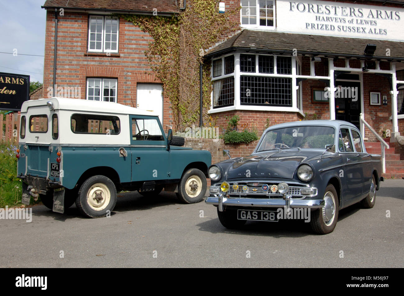 1961 Hillman Minx and Land Rover Series IIA classic British cars outside a country pub Stock Photo