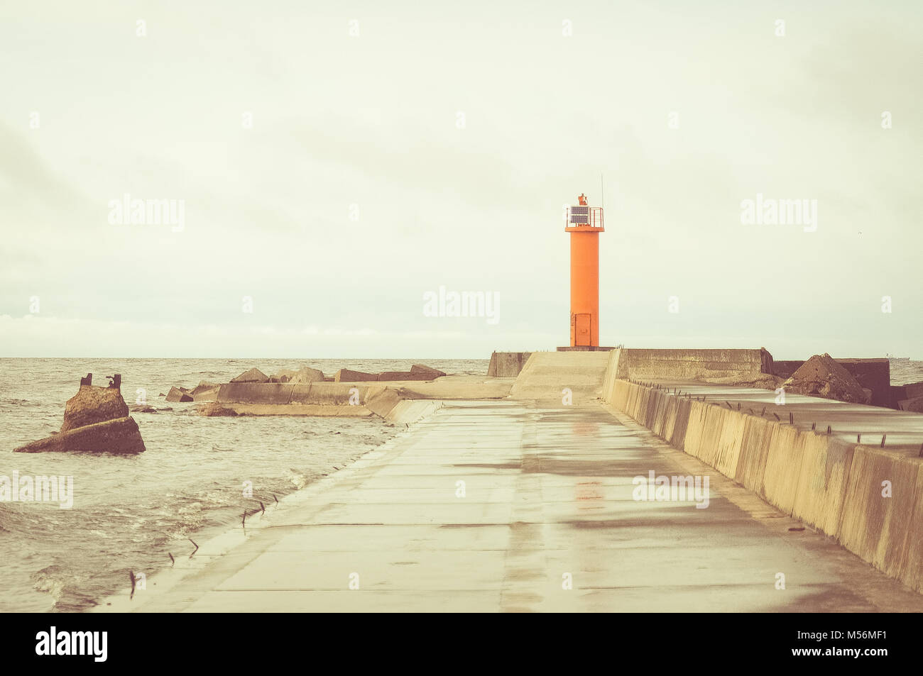 Orange lighthouse at the end of the jetty. Baltic sea. Stock Photo