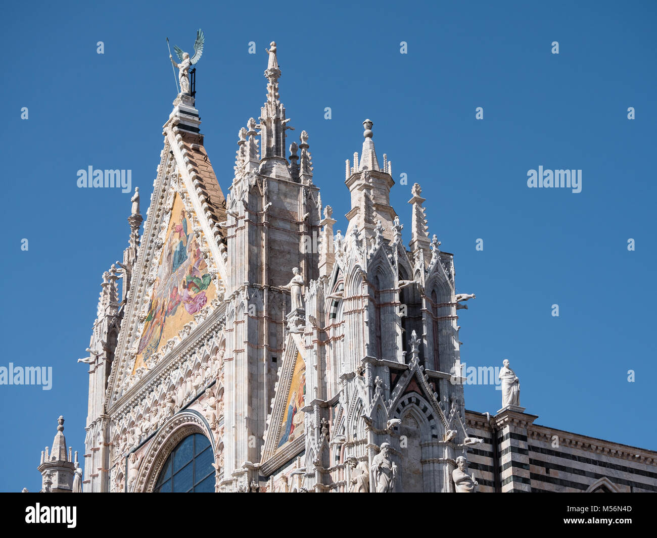 Exterior of the Cathedral of Siena showing the mosaics at the top of the west facade and scupltutes of philosophers, saints and other intricate decora Stock Photo