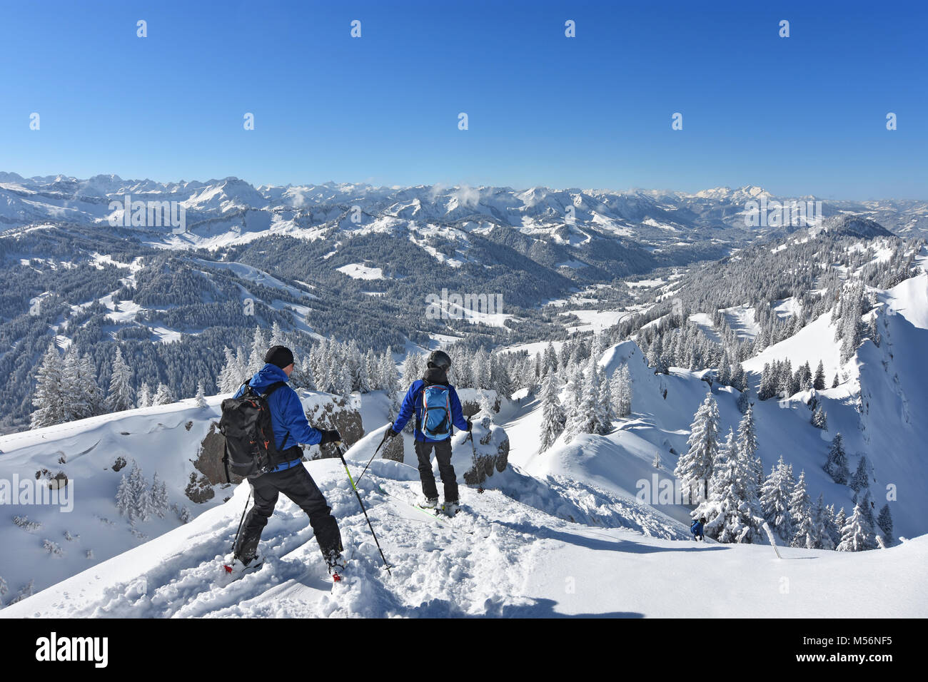 Two ski mountaineers are beginning their descent from the summit of Siplingerkopf (Allgaeu Alps) at a beautiful winter day. Bavaria, Germany Stock Photo