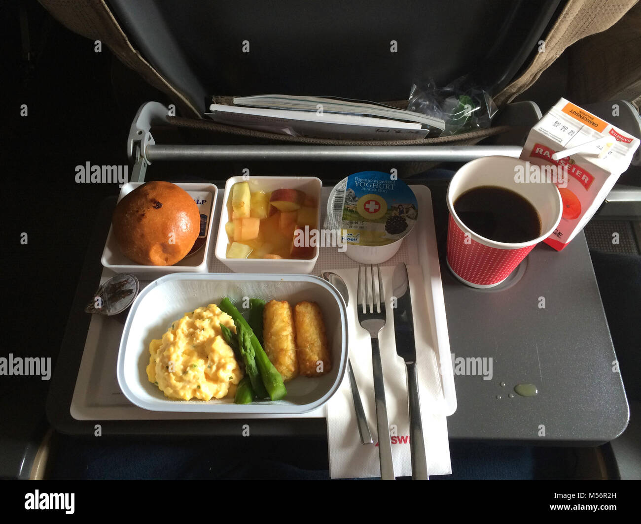 ZURICH, SWITZERLAND - MAR 31st, 2015: A breakfast meal with coffee, butter, bread, yogurt and scrambled eggs on a tray, onboard a longhaul flight to Singapore in economy class Stock Photo