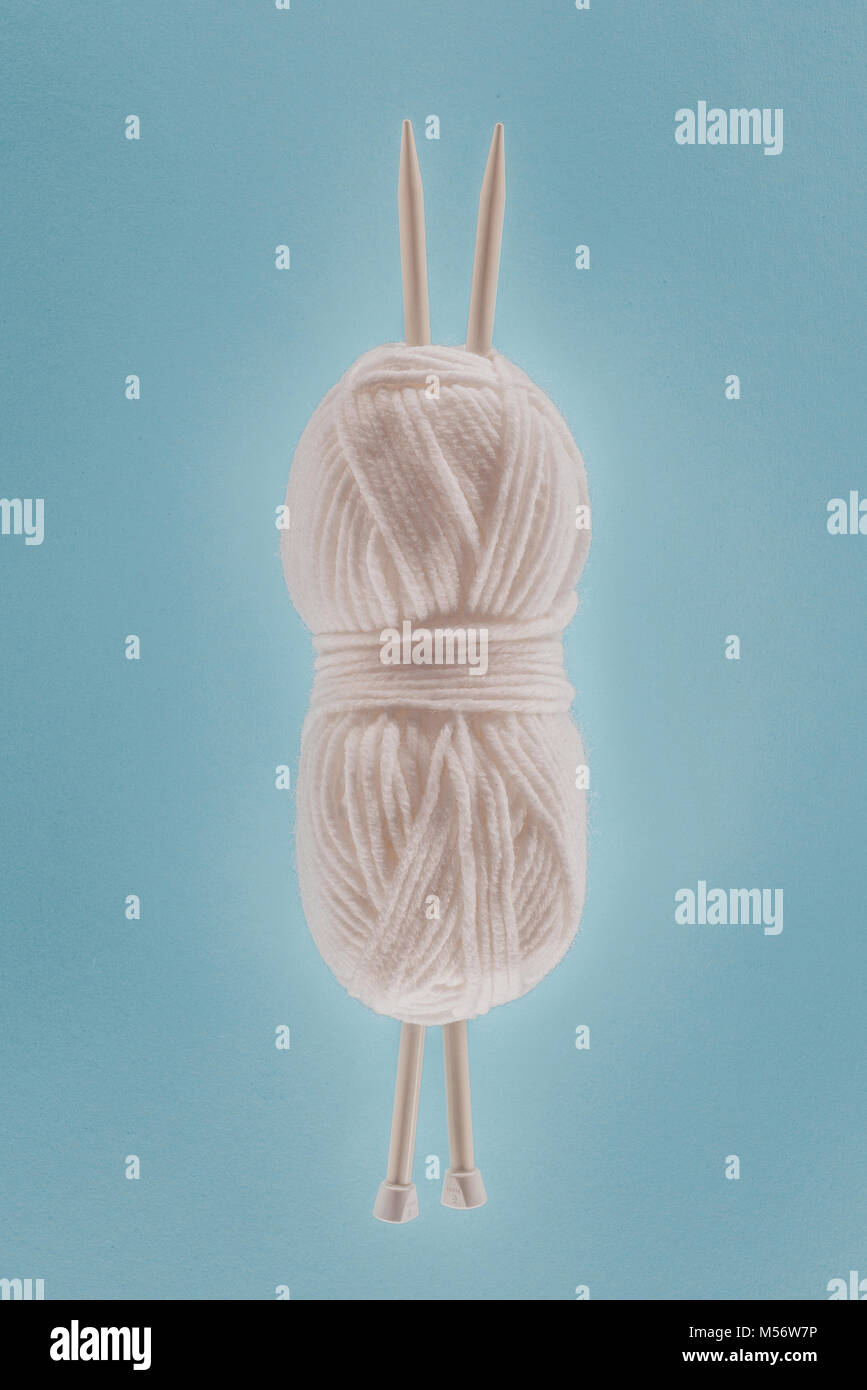 white knitting yarn ball with knitting needles, isolated on blue Stock