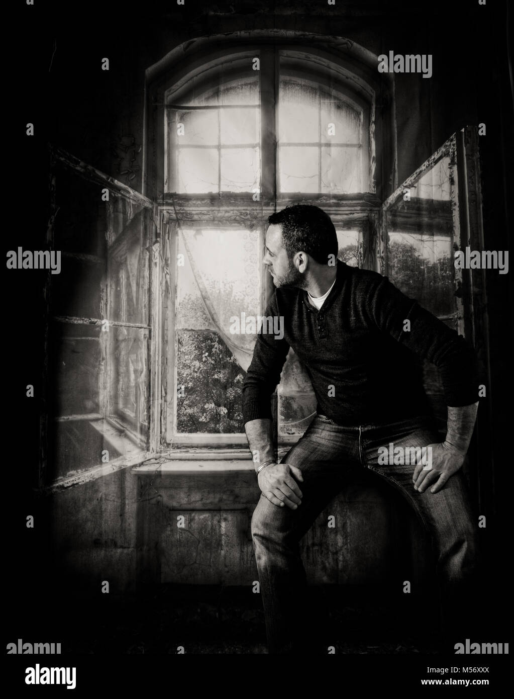 A studio shoot By Wiltshire Photographer Claire Allen of a male sitting on a windowsill looking out the window.. Stock Photo