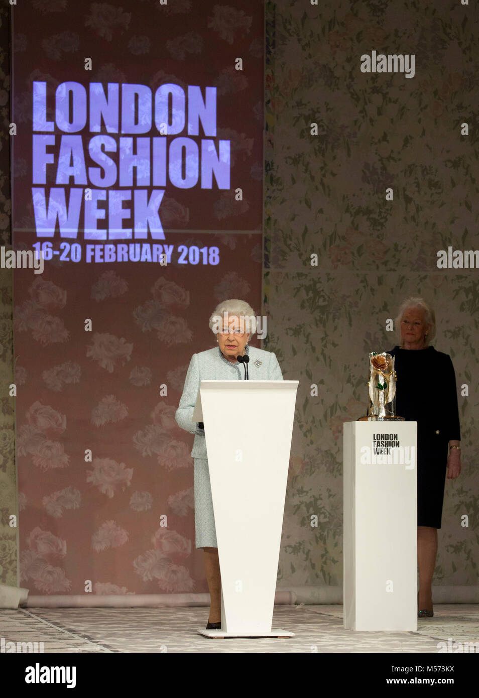 Queen Elizabeth II delivers a speech, watched by Angela Kelly, before presenting the inaugural Queen Elizabeth II Award for British Design to Richard Quinn following his Autumn/Winter 2018 London Fashion Week show at BFC Showspace, London. PRESS ASSOCIATION. Picture date: Tuesday February 20, 2018. Photo credit should read: Isabel Infantes/PA Wire Stock Photo