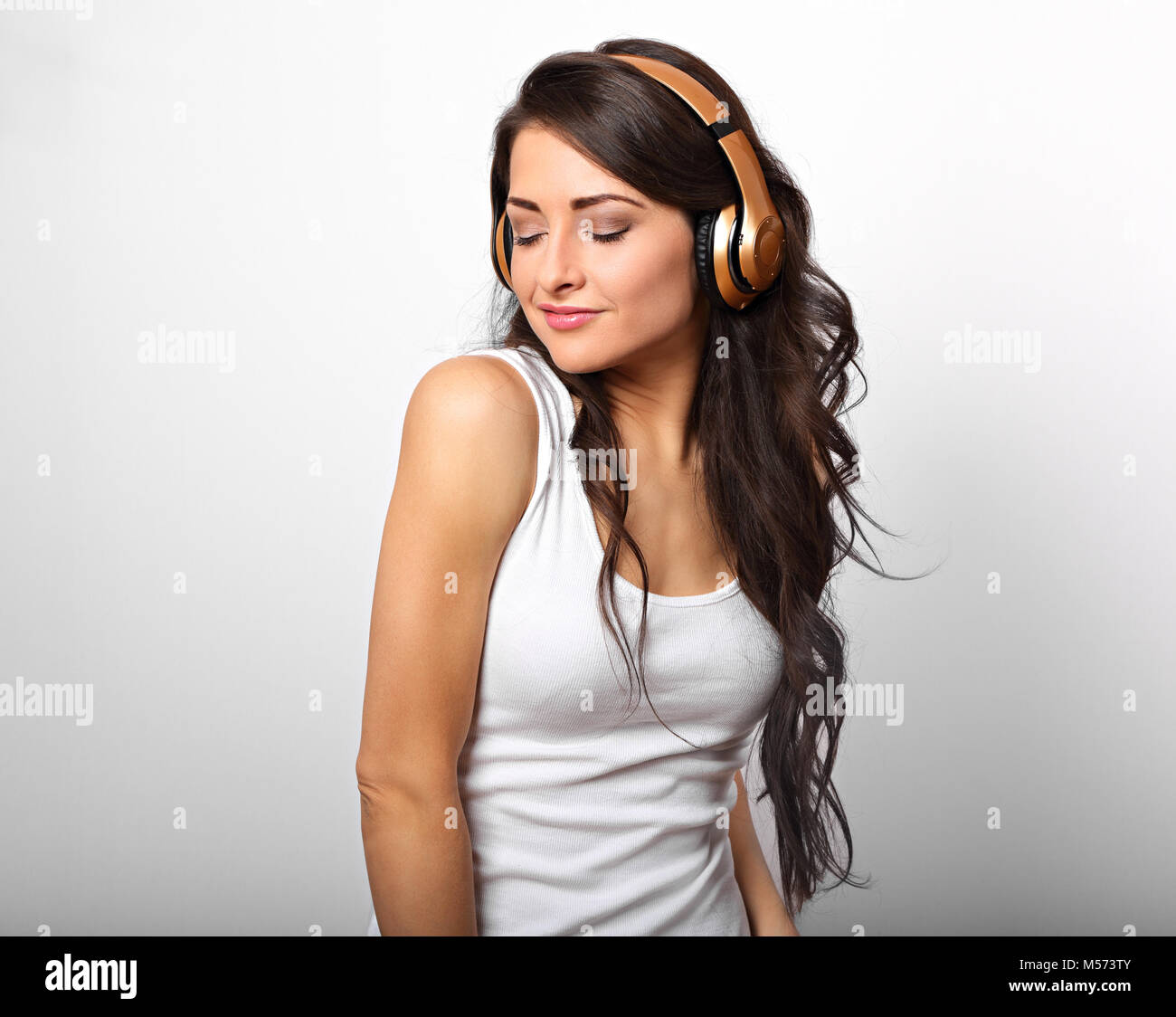 Beautiful happy long hair young woman in casual clothing listening the ...