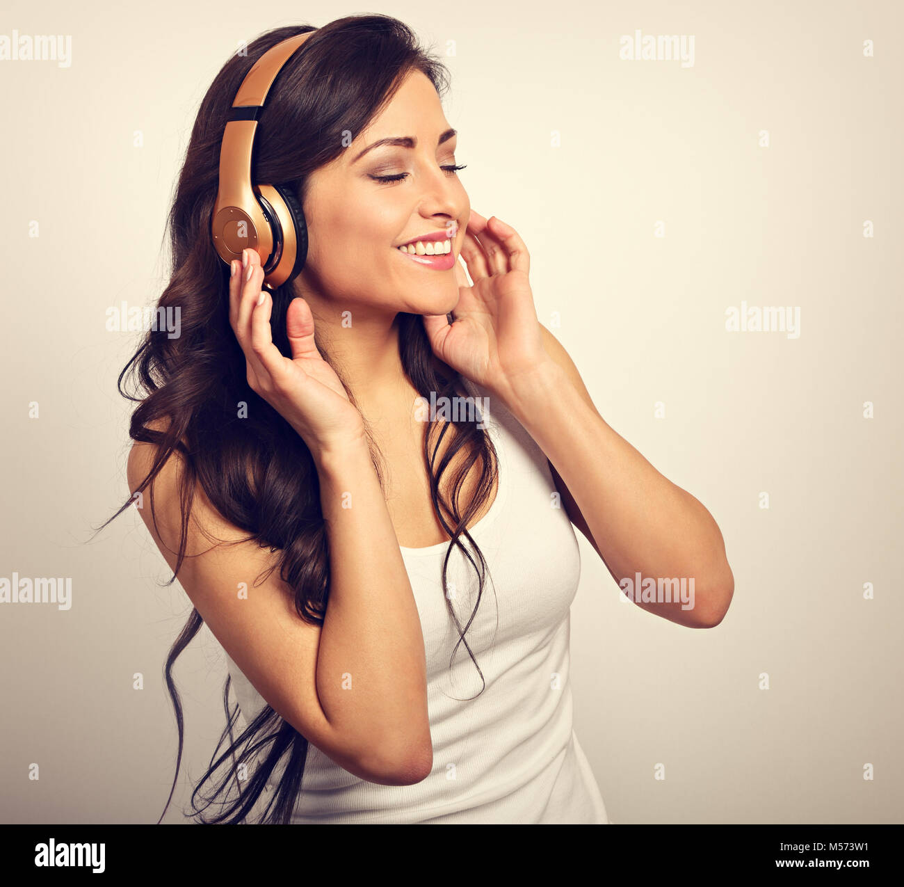 Beautiful happy long hair young woman in casual clothing listening the ...