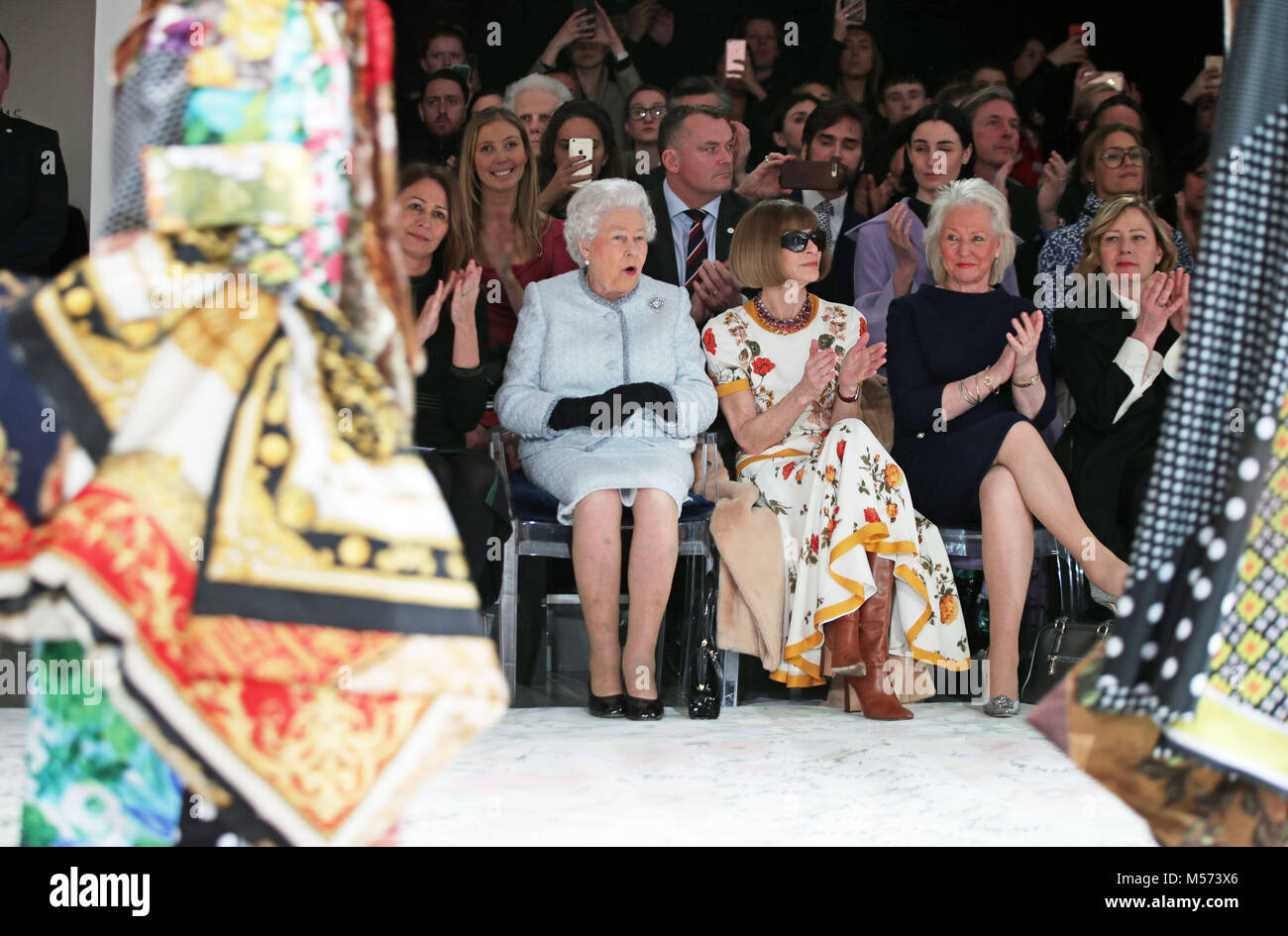 Queen Elizabeth II reacts as she sits with Anna Wintour (third right) and Caroline Rush (left), chief executive of the British Fashion Council (BFC) and royal dressmaker Angela Kelly (second right), as they view Richard Quinn's runway show before presenting him with the inaugural Queen Elizabeth II Award for British Design as she visits London Fashion Week's BFC Show Space in central London. Stock Photo