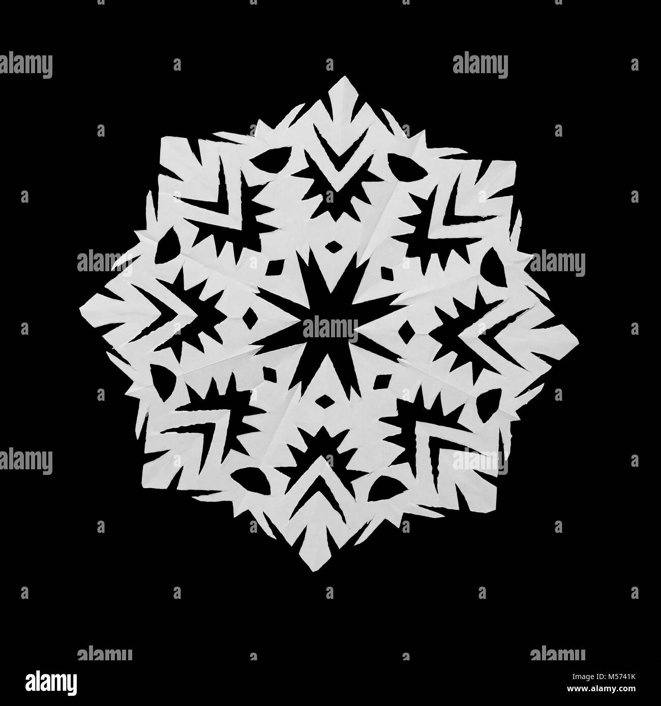 White snowflake cut out of paper lies on black background Stock Photo ...