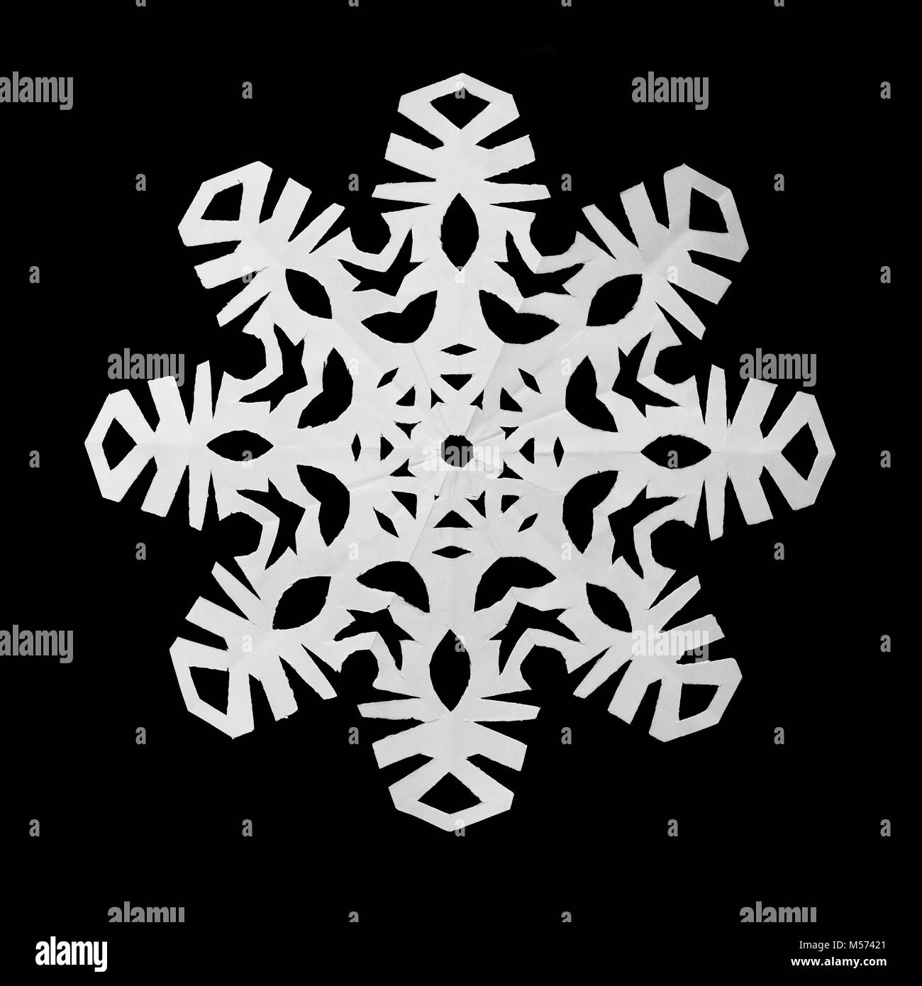 White snowflake cut out of paper lies on a black background Stock Photo ...