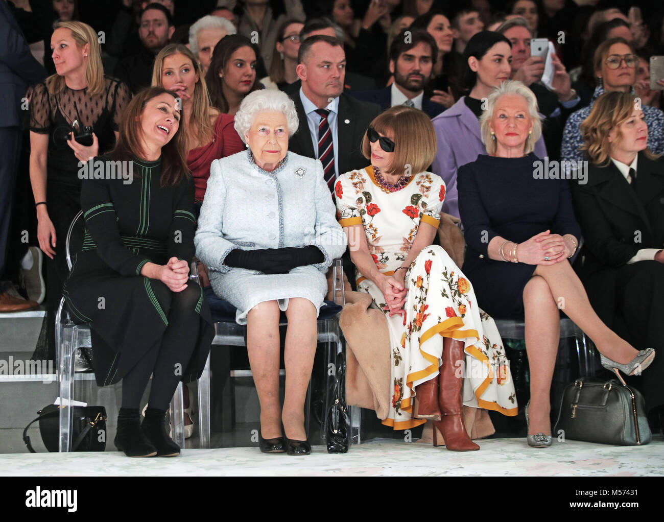Queen Elizabeth II sits with Anna Wintour (third right) and Caroline Rush, chief executive of the British Fashion Council (BFC) (left) and royal dressmaker Angela Kelly (second right), as they view Richard Quinn's runway show before presenting him with the inaugural Queen Elizabeth II Award for British Design as she visits London Fashion Week's BFC Show Space in central London. Stock Photo