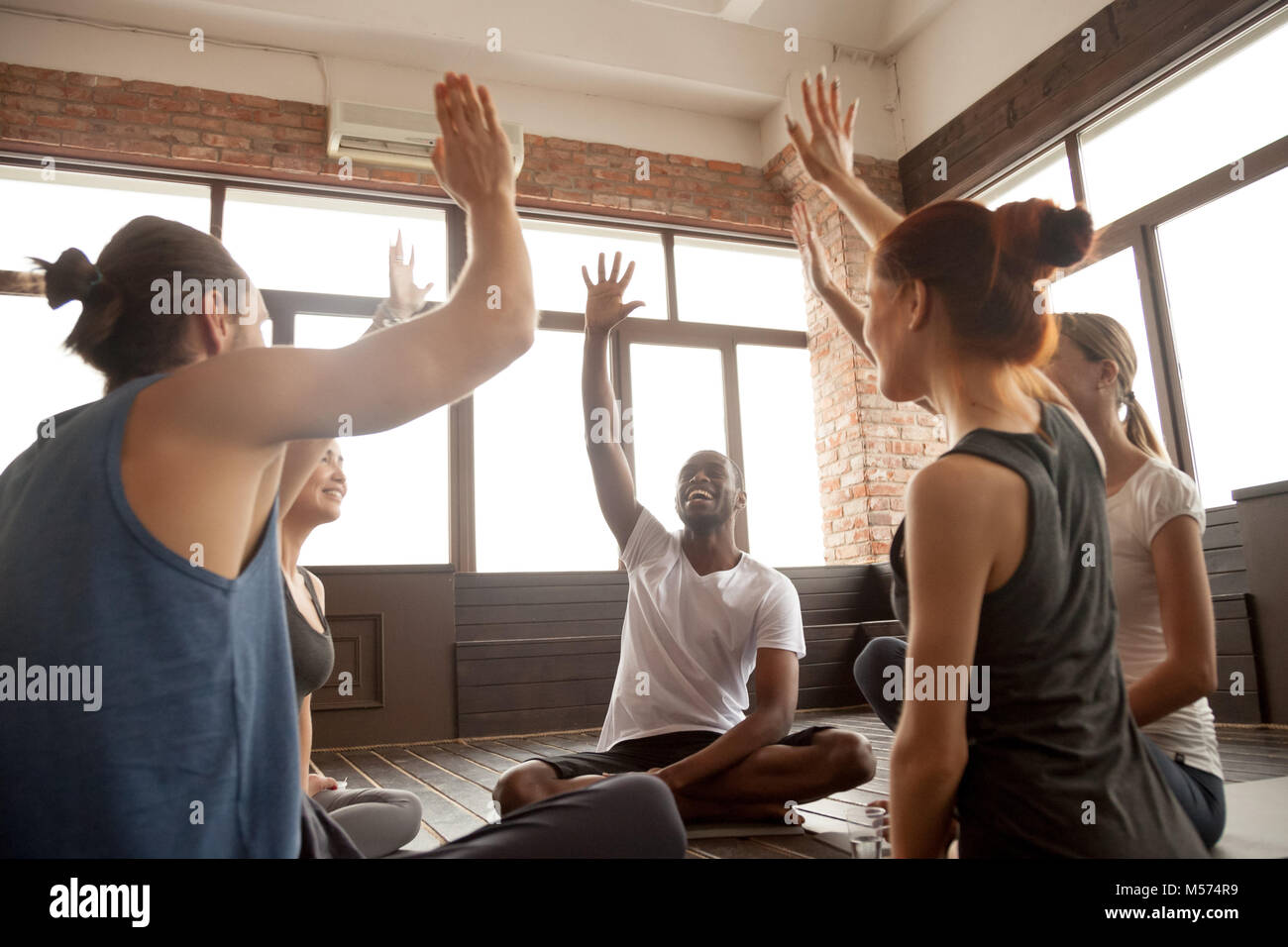 Happy diverse people raising hands together feeling motivated at Stock Photo
