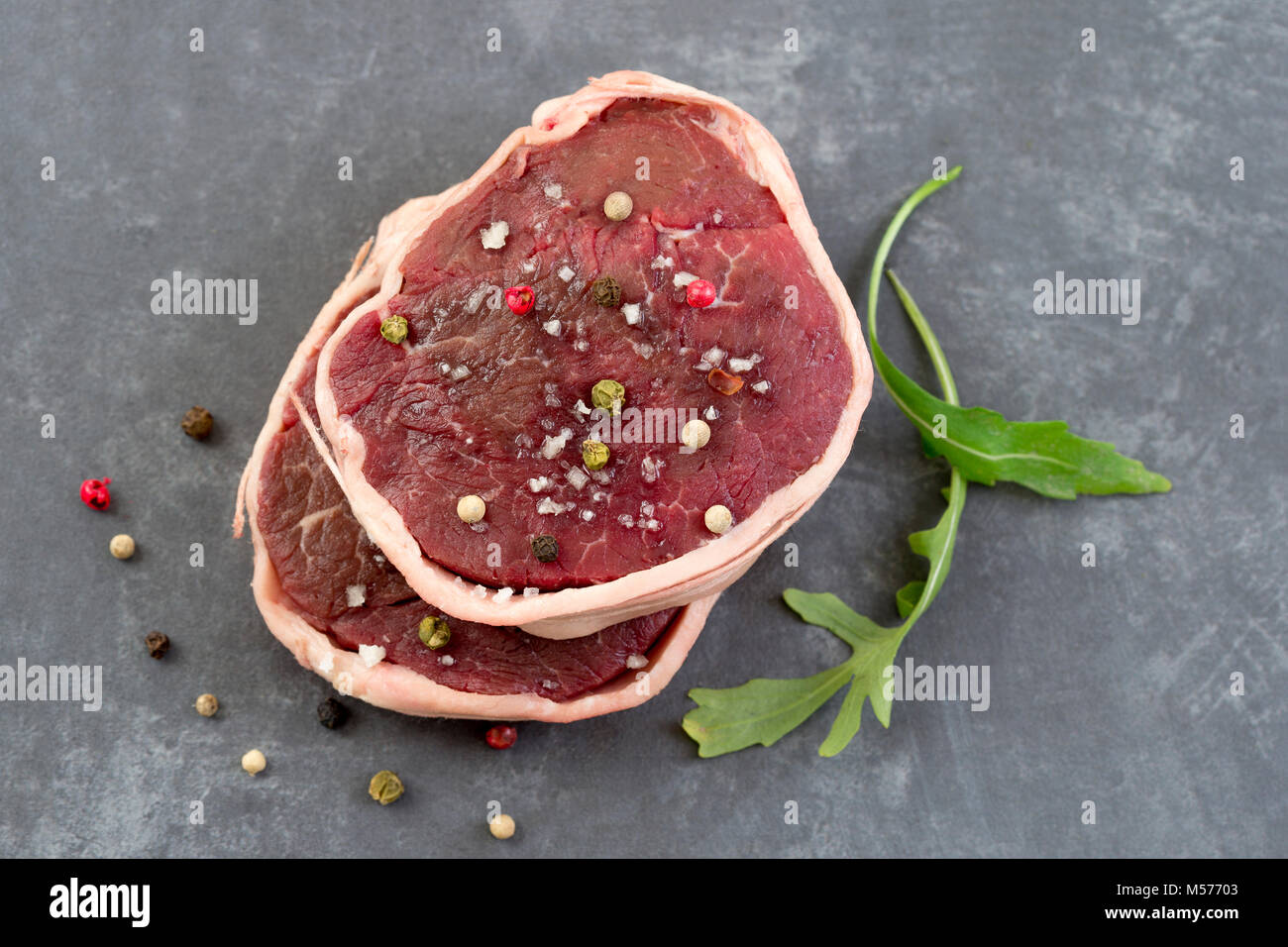 Tournedos: a small round thick cut from a fillet of beef grey slate background above view Stock Photo