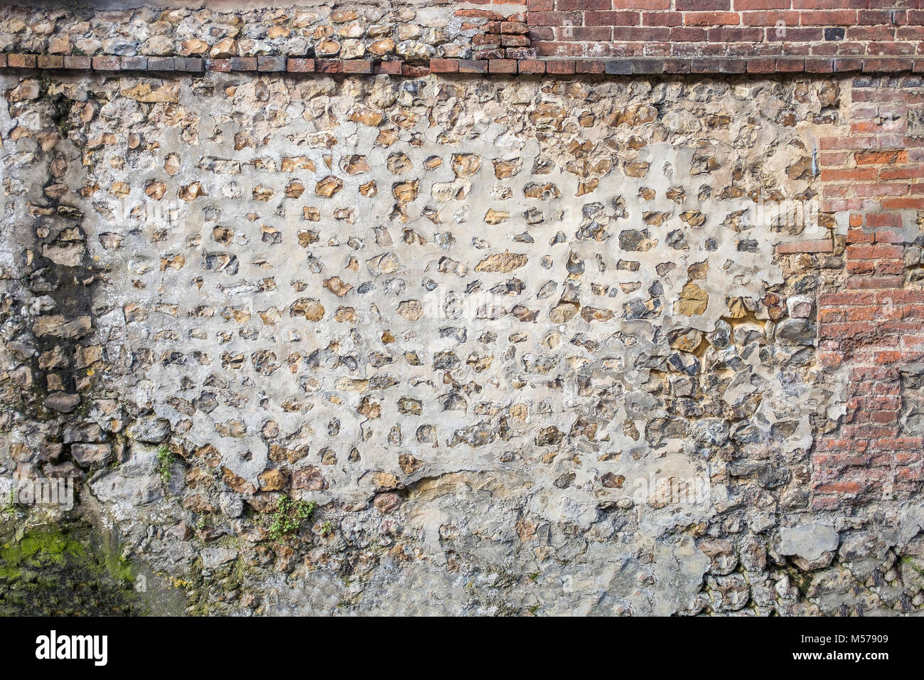 Panoramic image of a Decorative old and red brick flint wall with green and yellow vegetable moss Stock Photo