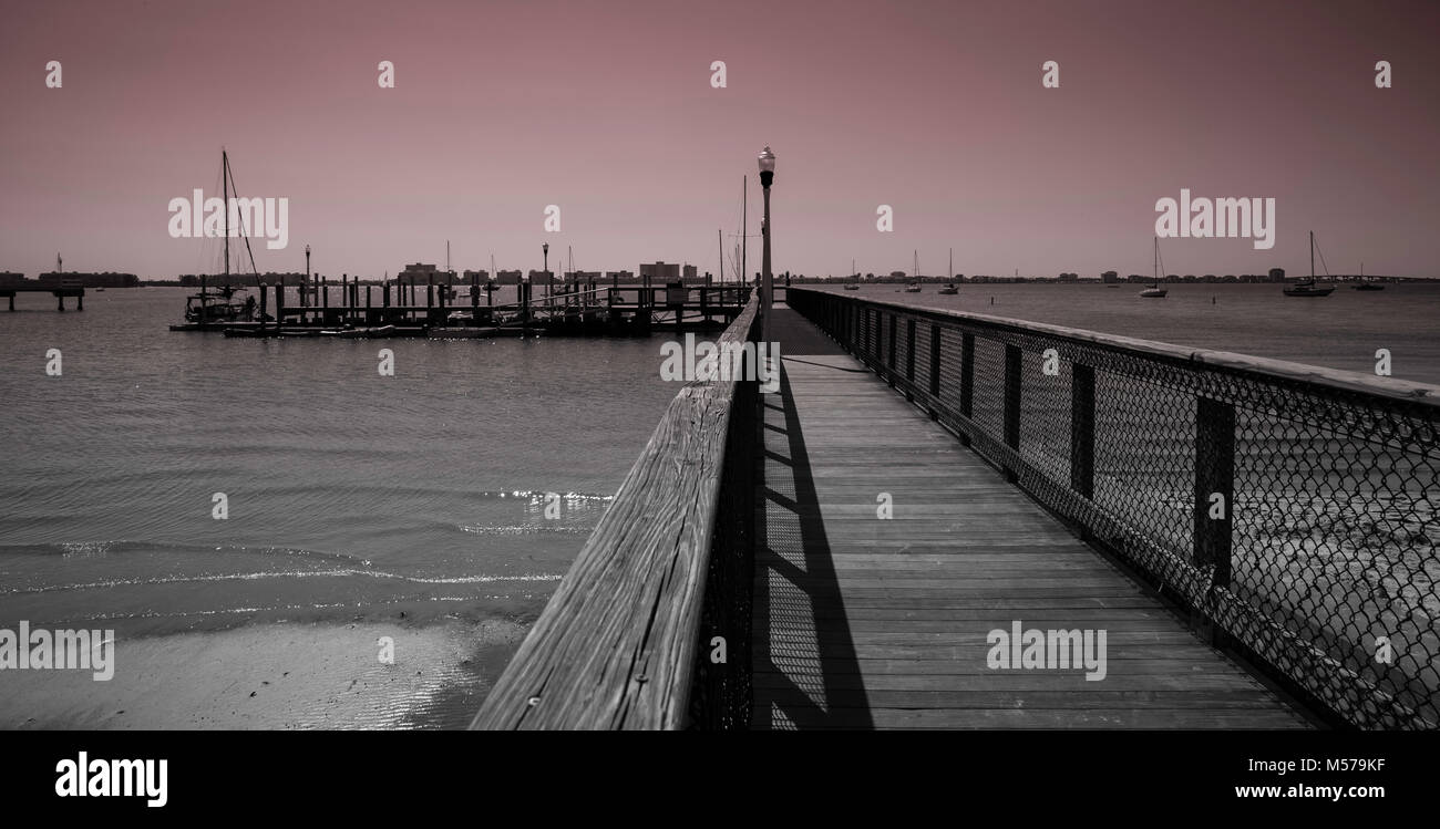 Wooden pier at Gulfport, Florida with sailboats in the bay, monochrome Stock Photo
