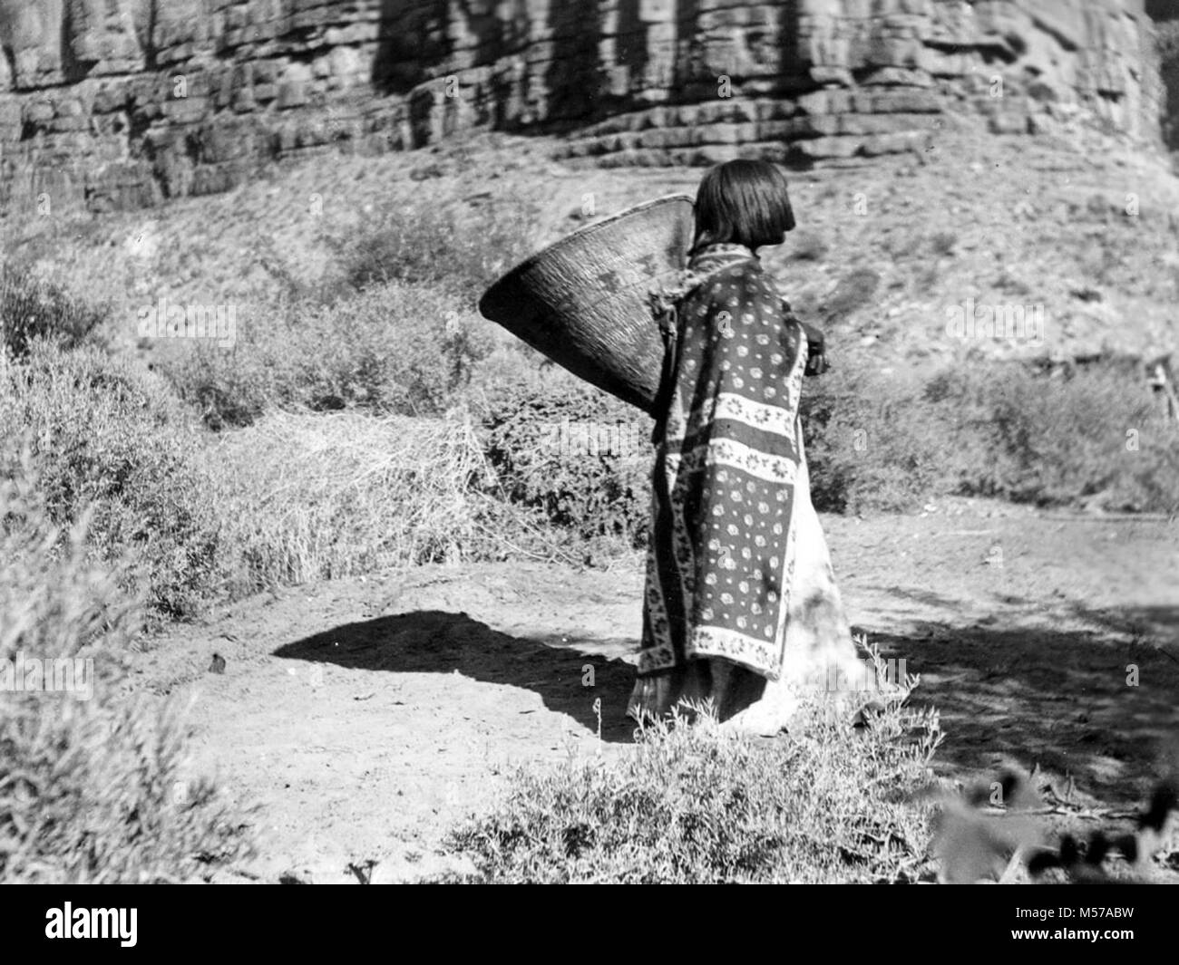 Grand Canyon Historic . SHORT- HAIRED HAVASUPAI WOMAN CARRYING A KATHAK BURDEN BASKET. FACE DOES NOT SHOW. CIRCA 1902. PEABODY. GRCA 24618 Stock Photo