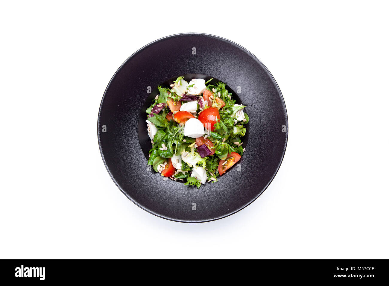 Italian mozzarella cheese and tomato salad with tomatoes and crisp crunchy fried bread cretins, view from above on a black  plate on white background. Stock Photo