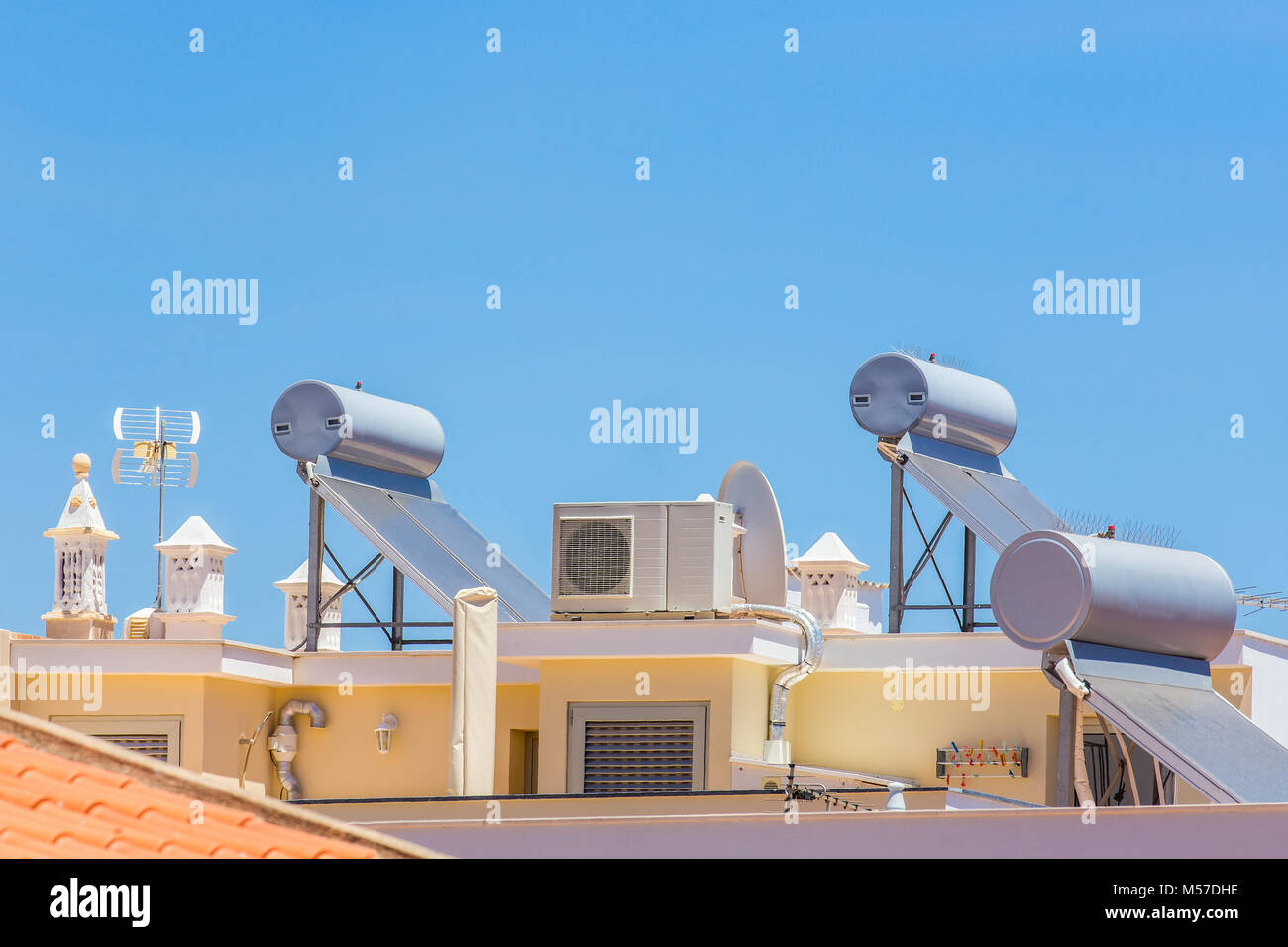 Solar panels and boilers on roof of building Stock Photo