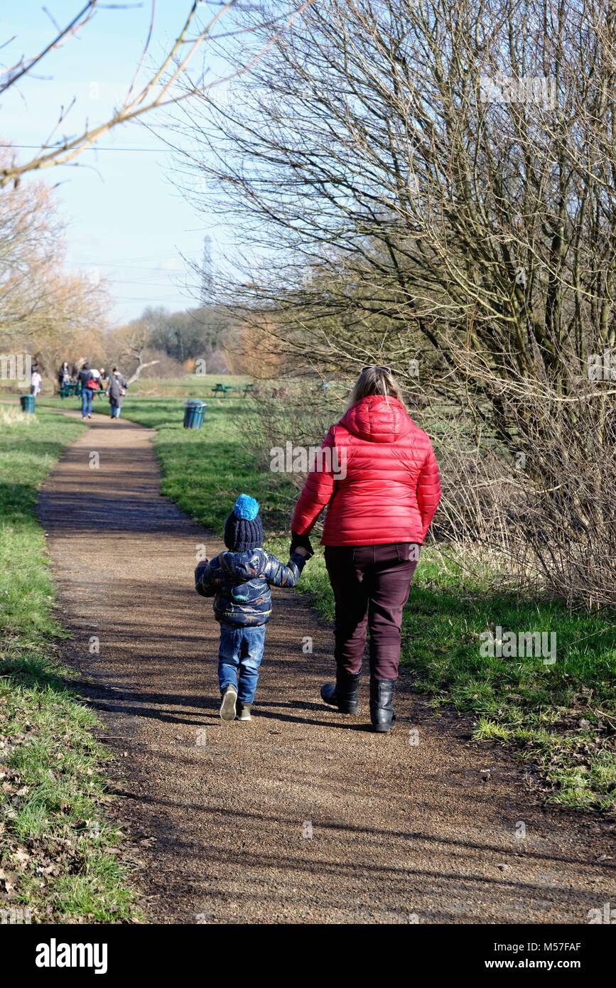 Rear view of mother and toddler walking on a footpath in a public park Chertsey Surrey England UK Stock Photo