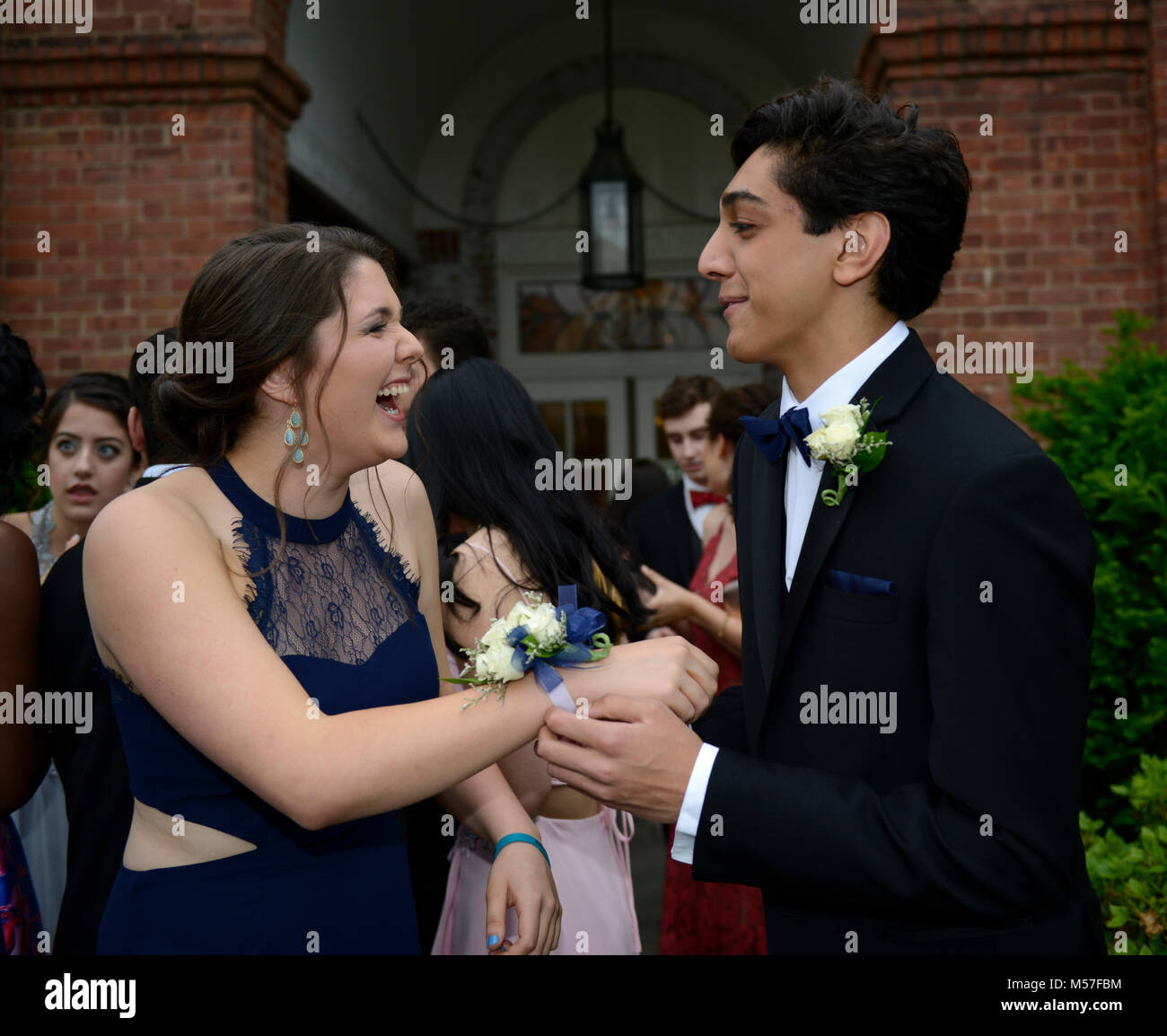 17 yr old high school juniors who just put on their boutonniere and wrist bouquet for prom.  He is Indian-American and she is caucasian. Stock Photo