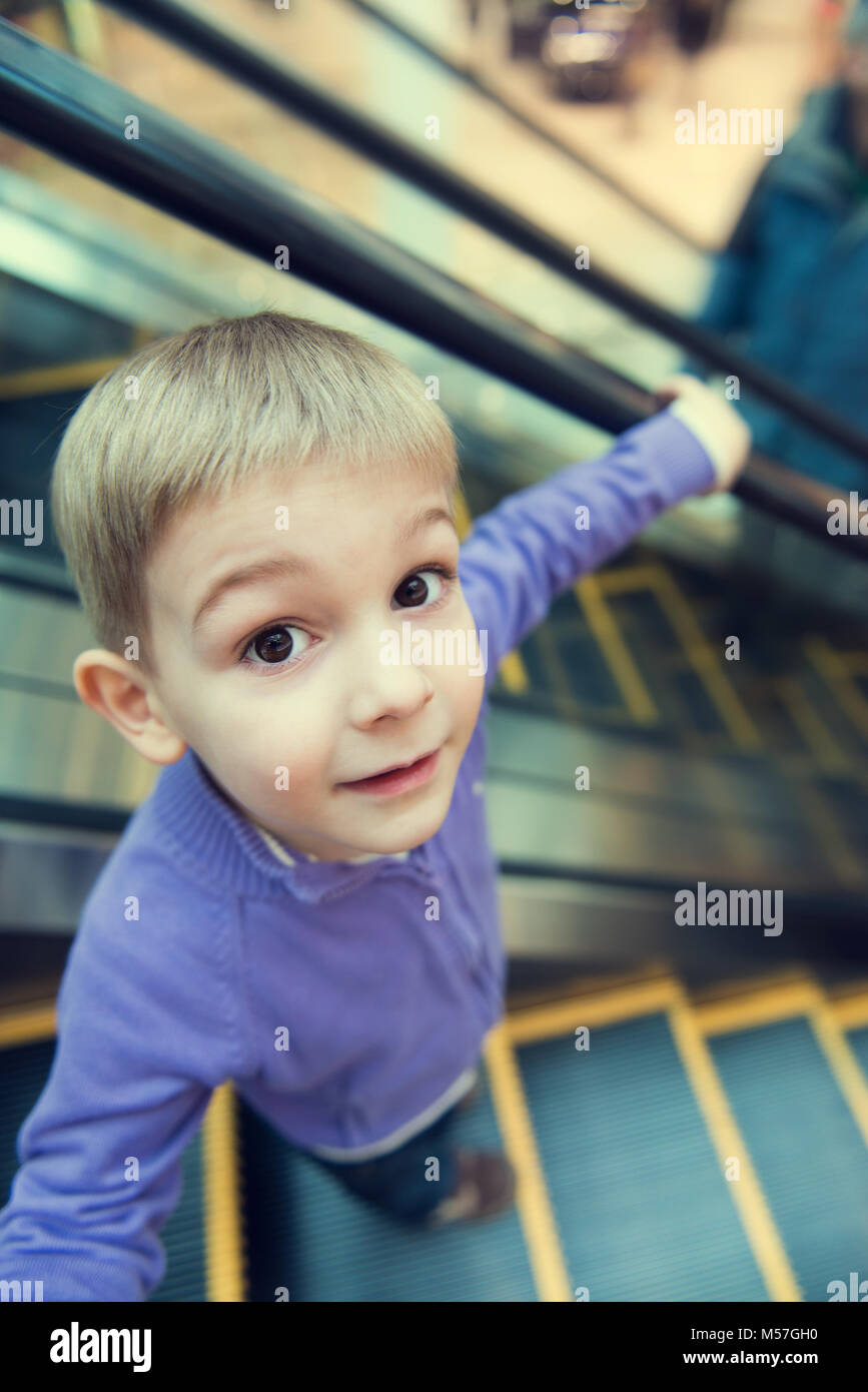 Cute little boy on escalator, funny wide-angle view. Stock Photo