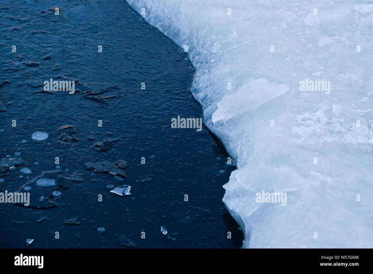 Ice hole in a frozen pond for winter swimming. The dark hole is covered