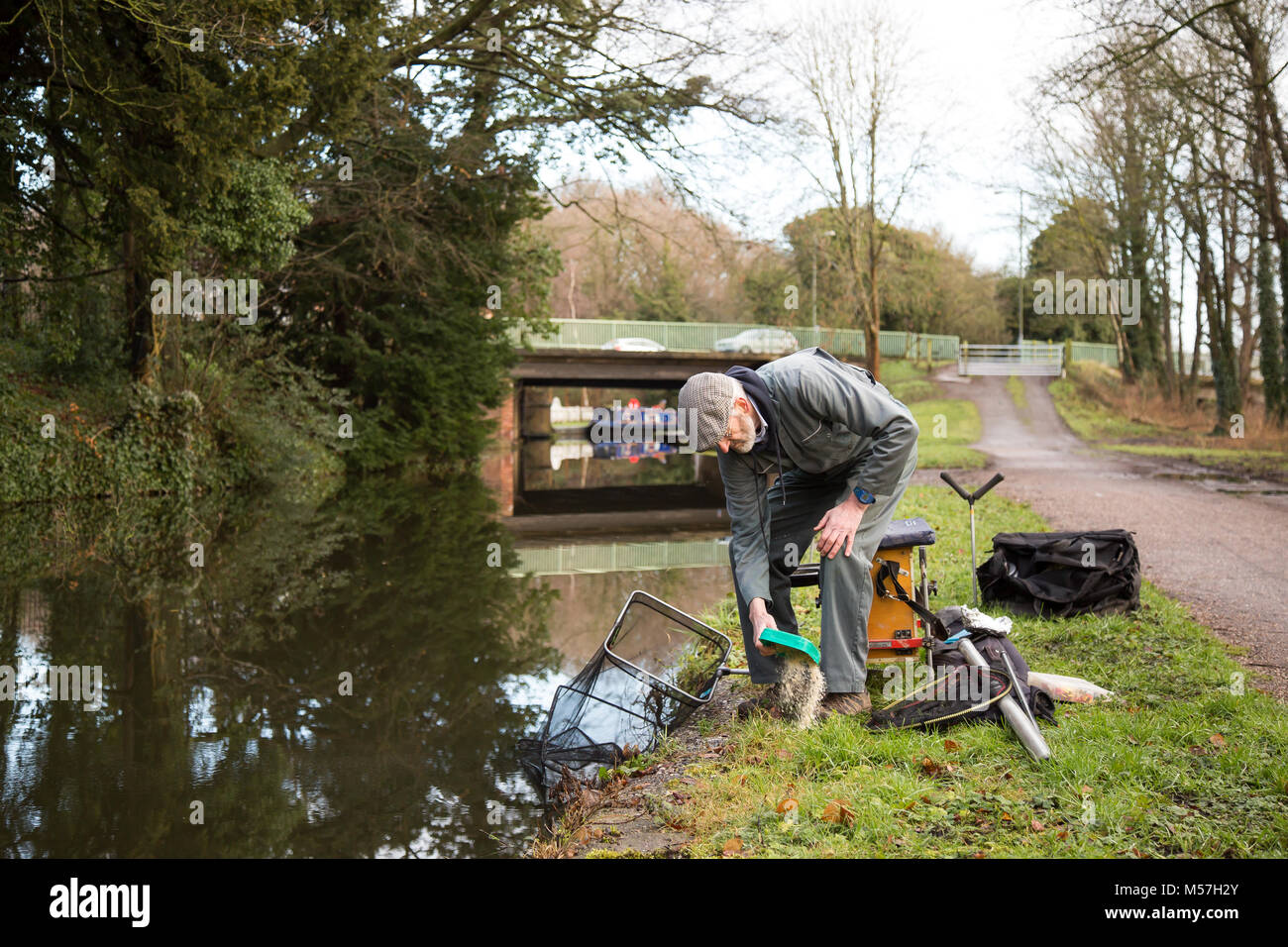 Lone fisherman putting away his tackle isolated on towpath after morning's fishing in UK canal. Angling UK. Stock Photo