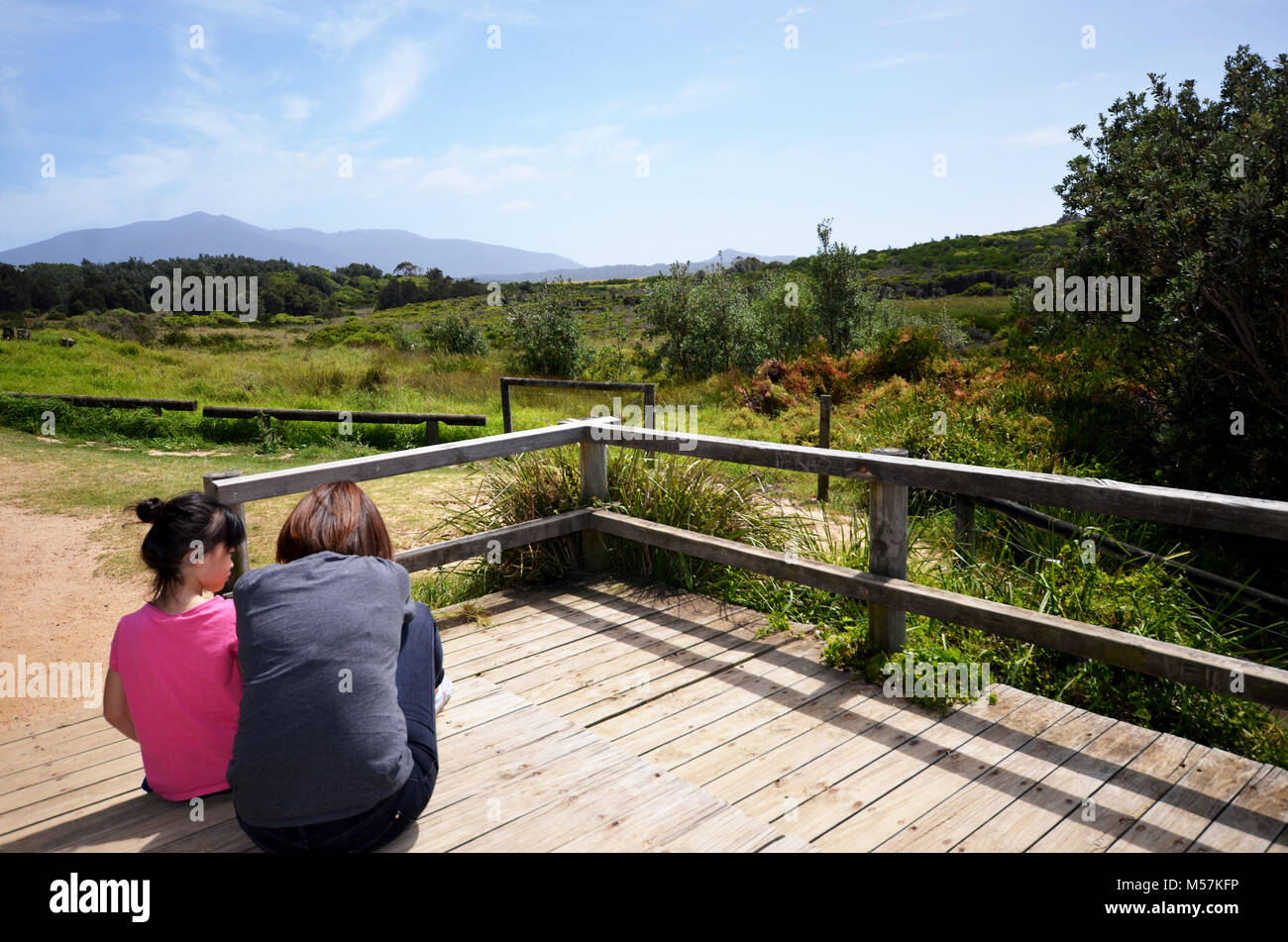 Mother and daughter sitting at viewing area with beautiful landscape in background Stock Photo