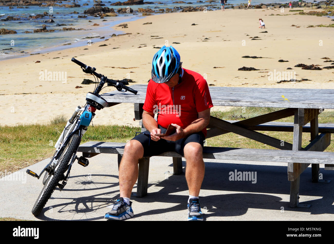 Self-isolation Man resting after cycling and checking mobile phone Stock Photo
