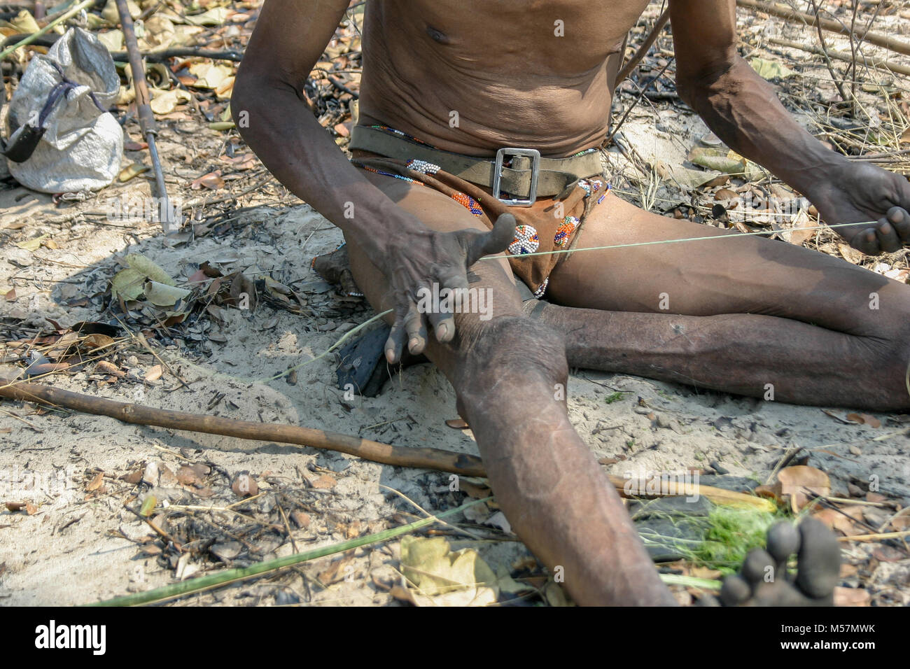 Members of the San Tribe using traditional methods to make the string of a bow. Stock Photo