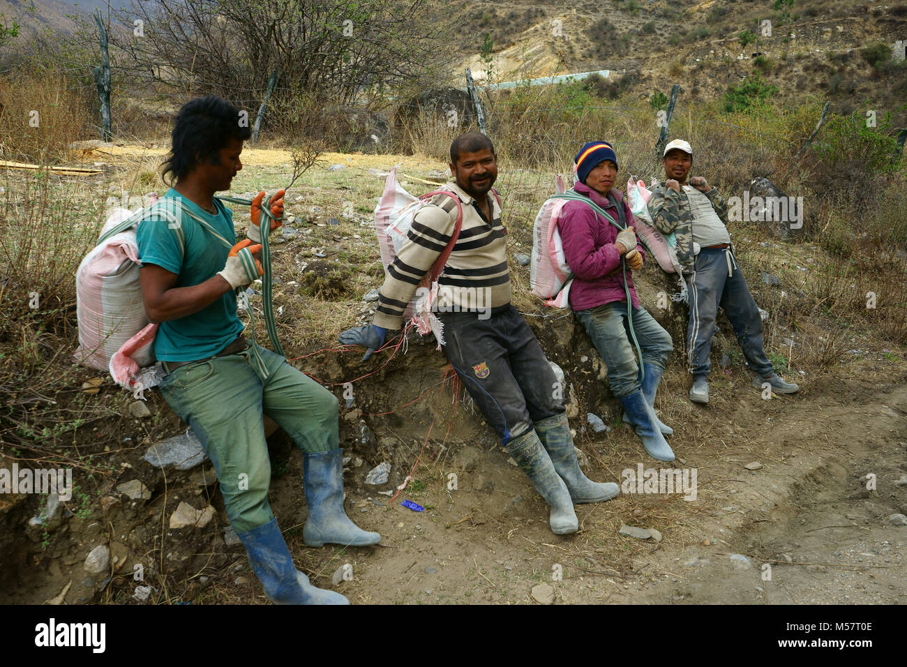 Porters from Bangladesh carrying cement bags to constructon site resting, Paro Valley, Bhutan Stock Photo