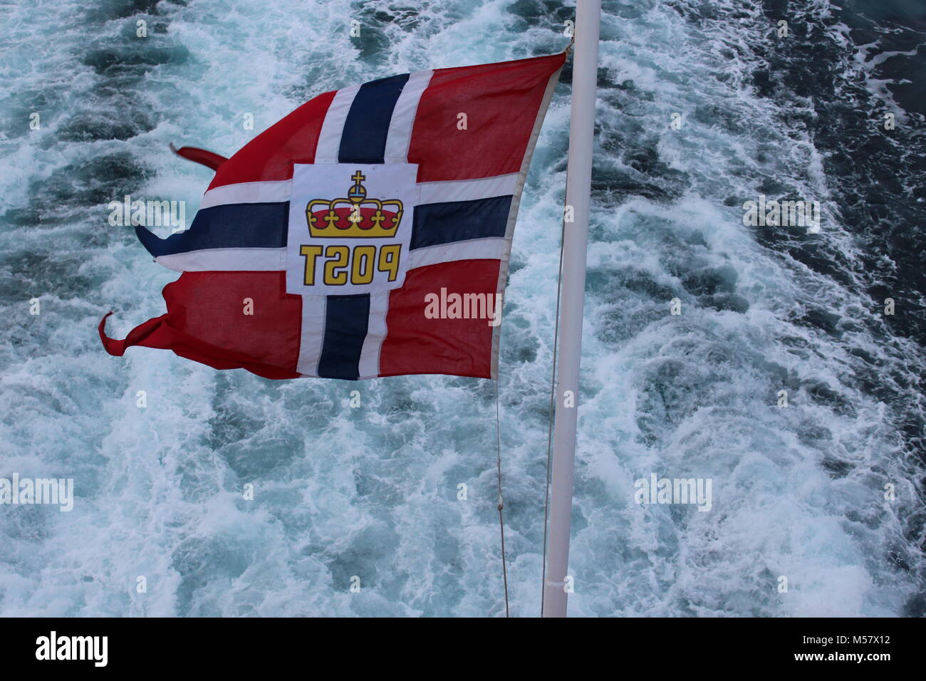 Norwegian Post flag flying fully extended at back of Hurtigruten cruise